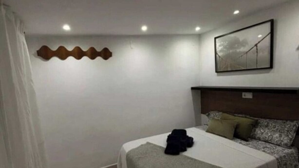 Une chambre d’hôtel avec un lit, une tête de lit, une œuvre d’art accrochée au mur et un rideau.