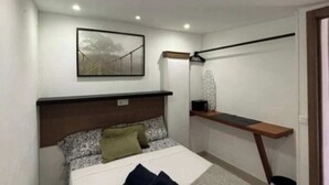 A bedroom with a bed, a bedside table, a hanging light, a wall-mounted shelf, and a framed picture. - Apartment 1 beach Almayate (Almayate Bajo)