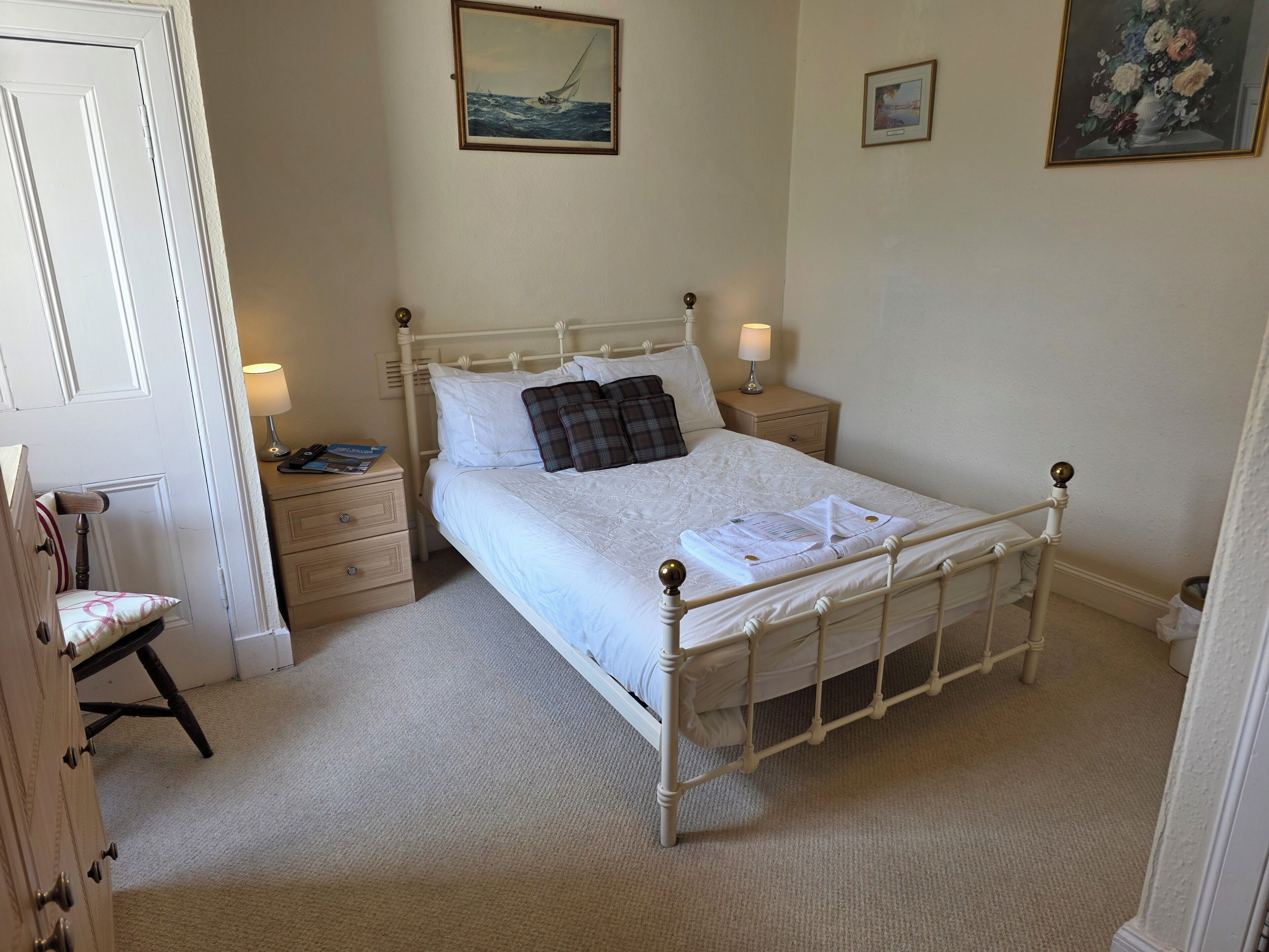 A neatly arranged bedroom with a single bed, bedside tables, a chair, and a door.