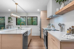 A modern kitchen with a central island, built-in appliances, and a pendant light. - Hidden Speakeasy • Hot Tub • Sauna • Private Woods (Gatlinburg)