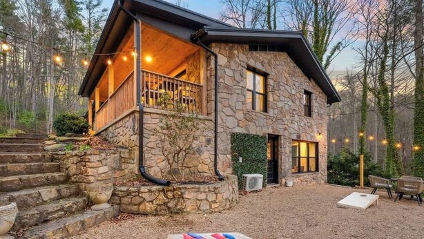 Una casa de piedra con balcón, un pozo de fuego y una terraza de madera.