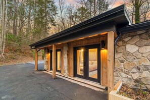 Eine Lodge mit Natursteinfassade, Holzbalken und großen Fenstern.