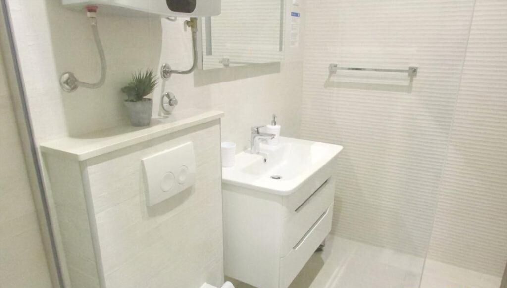 Une salle de bain moderne avec un lavabo blanc, un miroir et un porte-serviettes.