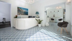 Une cuisine moderne avec un îlot central blanc, un sol à motifs bleus et un tableau représentant un paysage côtier.