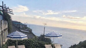 Un espace piscine aménagé sur le toit, avec des chaises longues et des parasols, offrant une vue sur le paysage côtier.