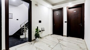 Un pasillo moderno y luminoso con suelo de mármol, una escalera y dos puertas de madera oscura con la leyenda 304.