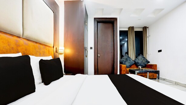Habitación de hotel con una cama grande, un escritorio con silla, un armario y una puerta que da a otra habitación.