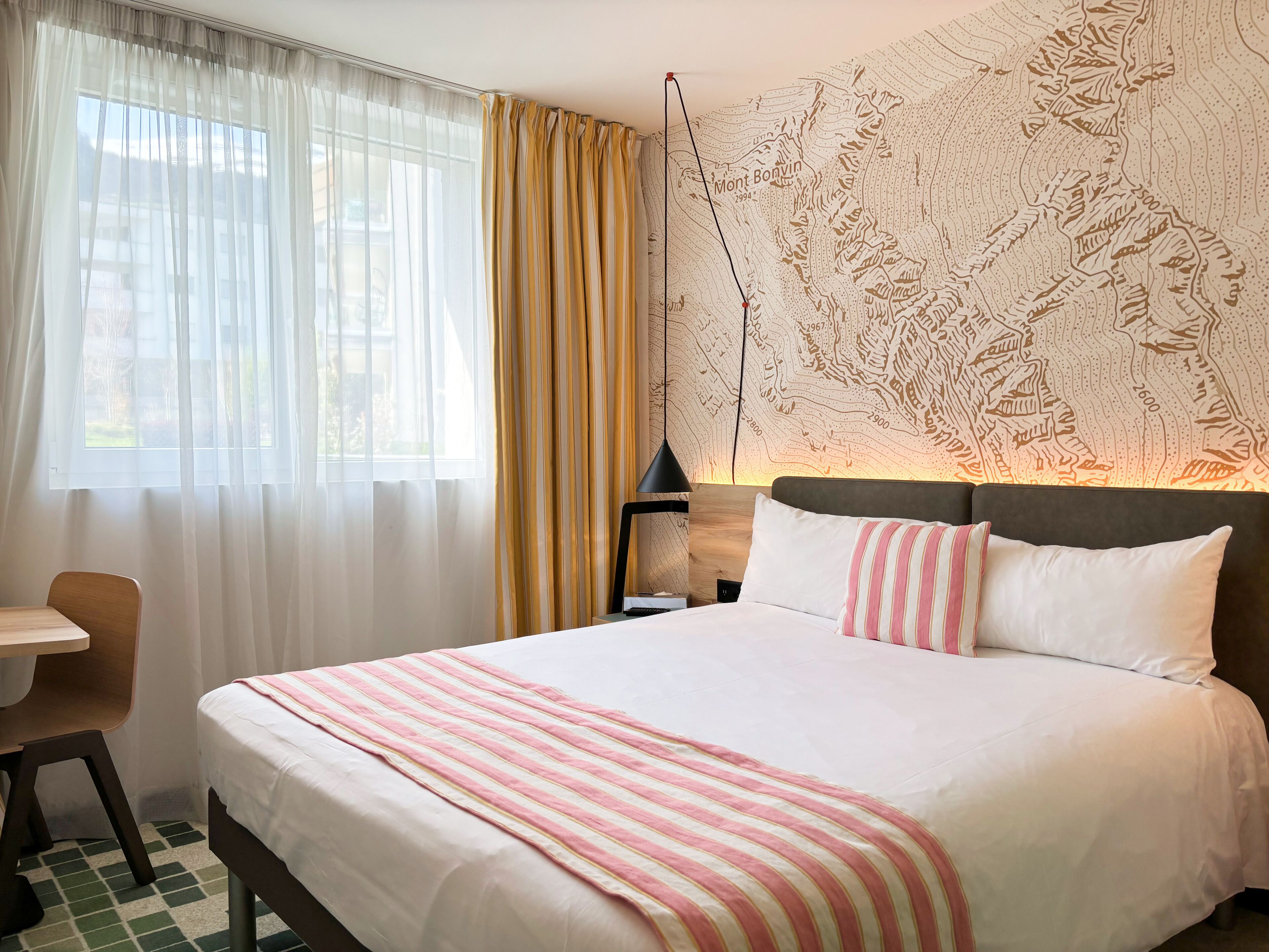 Een hotelkamer met een groot bed, een bureau en een kaart aan de muur.
