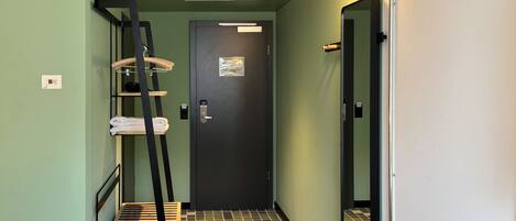 A narrow hallway with a wooden ladder, a door, and a mirror.