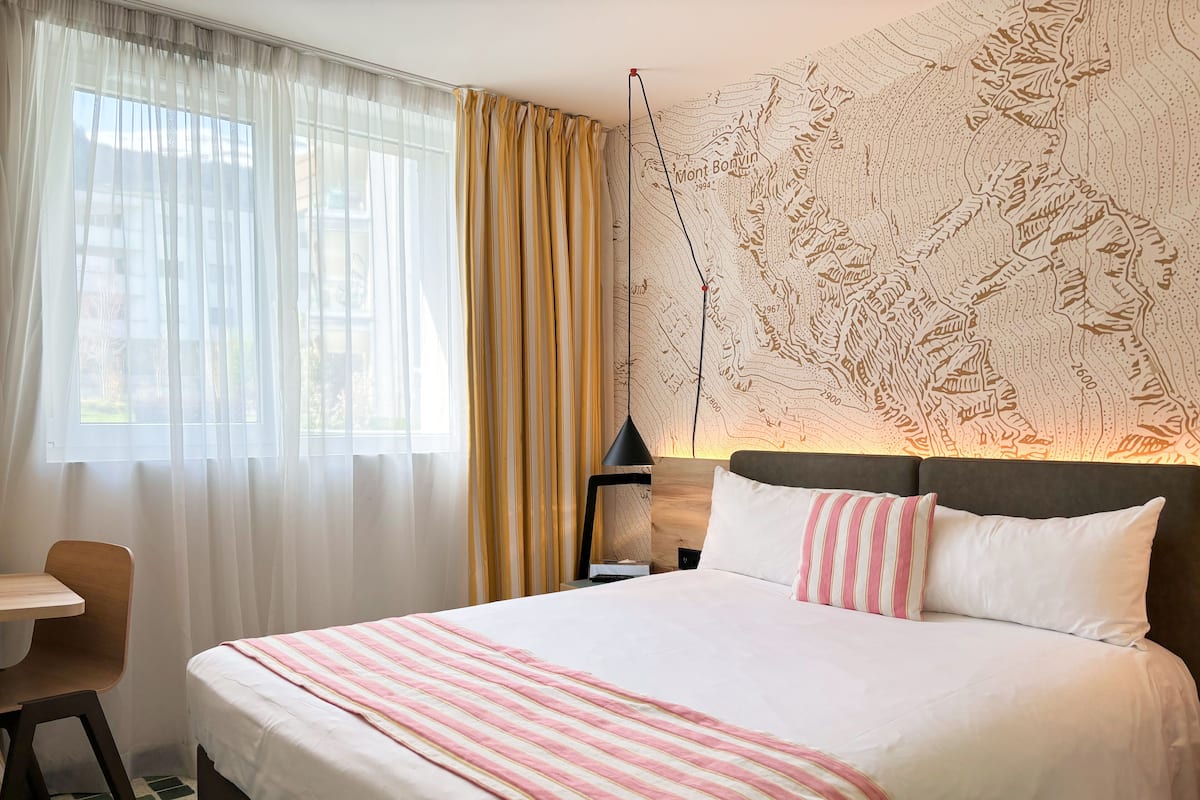 Una habitación de hotel con una cama grande, un escritorio y un mapa en la pared.