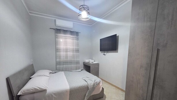Una camera da letto con un letto, comodino, televisore e armadio.