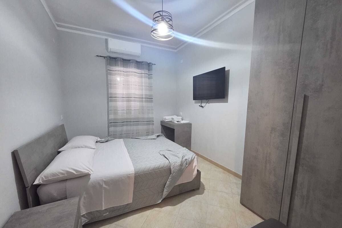 Une chambre à coucher comprenant un lit, une table de chevet, une télévision et une armoire.