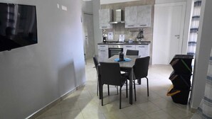 Una cucina moderna con zona pranzo, una TV a schermo piatto montata a parete e una scala che conduce a un altro livello.