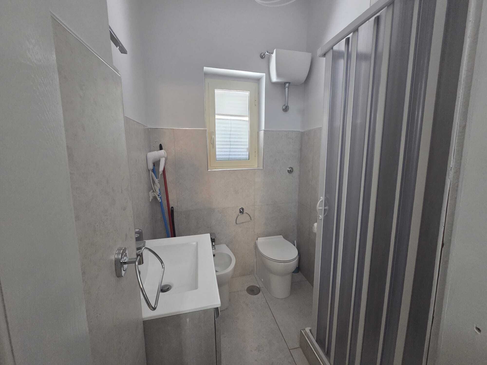 Une salle de bain comprenant des toilettes, un bidet, un lavabo et un espace douche.