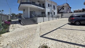 Un edificio di due piani con un balcone, una scala e un'auto parcheggiata.