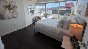 Un dormitorio moderno con una cama grande, un sofá y vistas a la ciudad.
