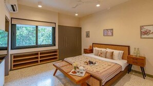 A bedroom with a bed, bedside table, wardrobe, and a window with a view of trees. - Cozy Nest 4Bhk Private Villa with Private Pool, Anjuna Beach North Goa (Vagator)