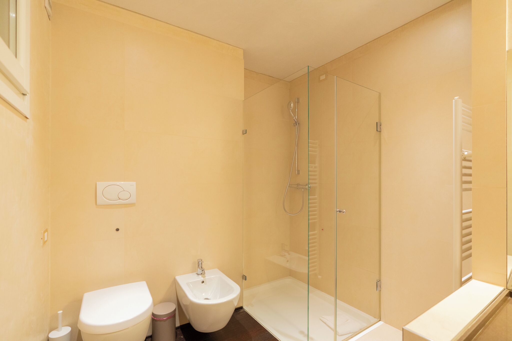 A modern bathroom with a toilet, bidet, and glass-enclosed shower.