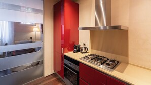 A modern kitchen with a gas stove, oven, and red cabinets. - Residenza Rubiani con Vista Arena (Verona)