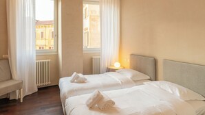 A hotel room with two beds, a chair, a radiator, and a window with curtains. - Residenza Rubiani con Vista Arena (Verona)