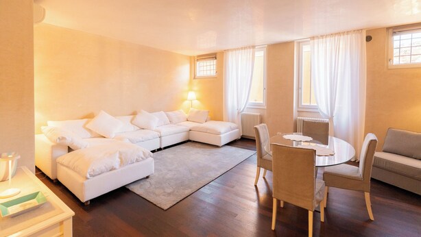 A modern living room with a sectional sofa, a round dining table with chairs, a coffee table, and a fireplace. - Residenza Rubiani con Vista Arena (Verona)