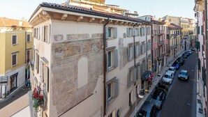 A row of buildings with a prominent hotel sign, a narrow street with parked cars, and a clear view of the street from a high vantage point. - Residenza Rubiani con Vista Arena (Verona)