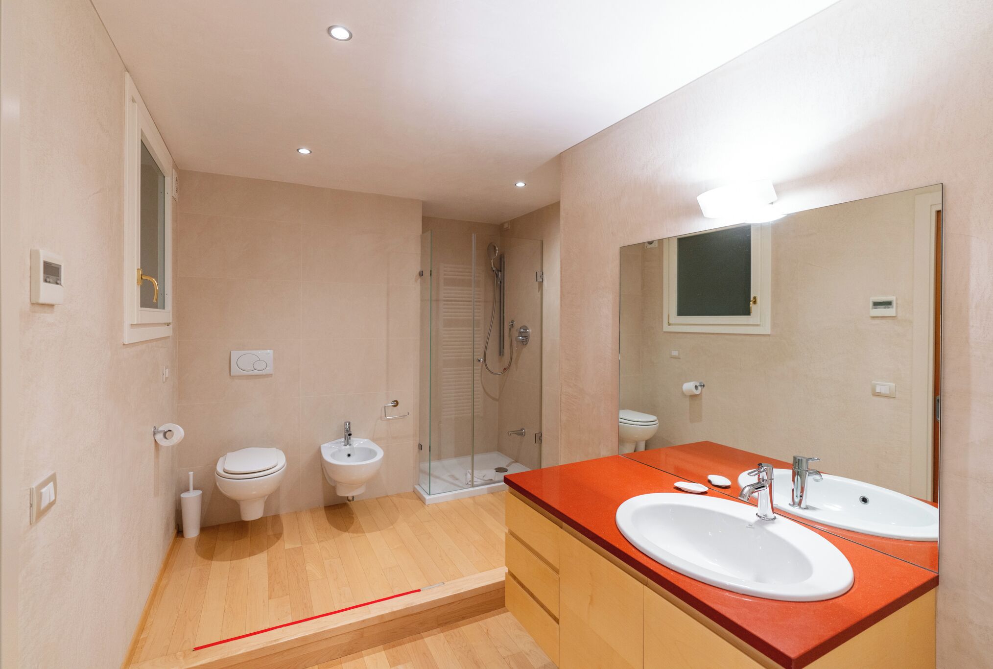 A modern bathroom with two sinks, a shower, and a toilet.