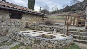 A stone building with a tiled roof, a stone pathway, and a wooden gate.