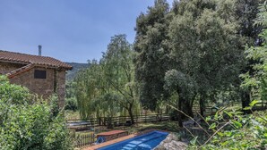A swimming pool surrounded by lush greenery and a stone building.