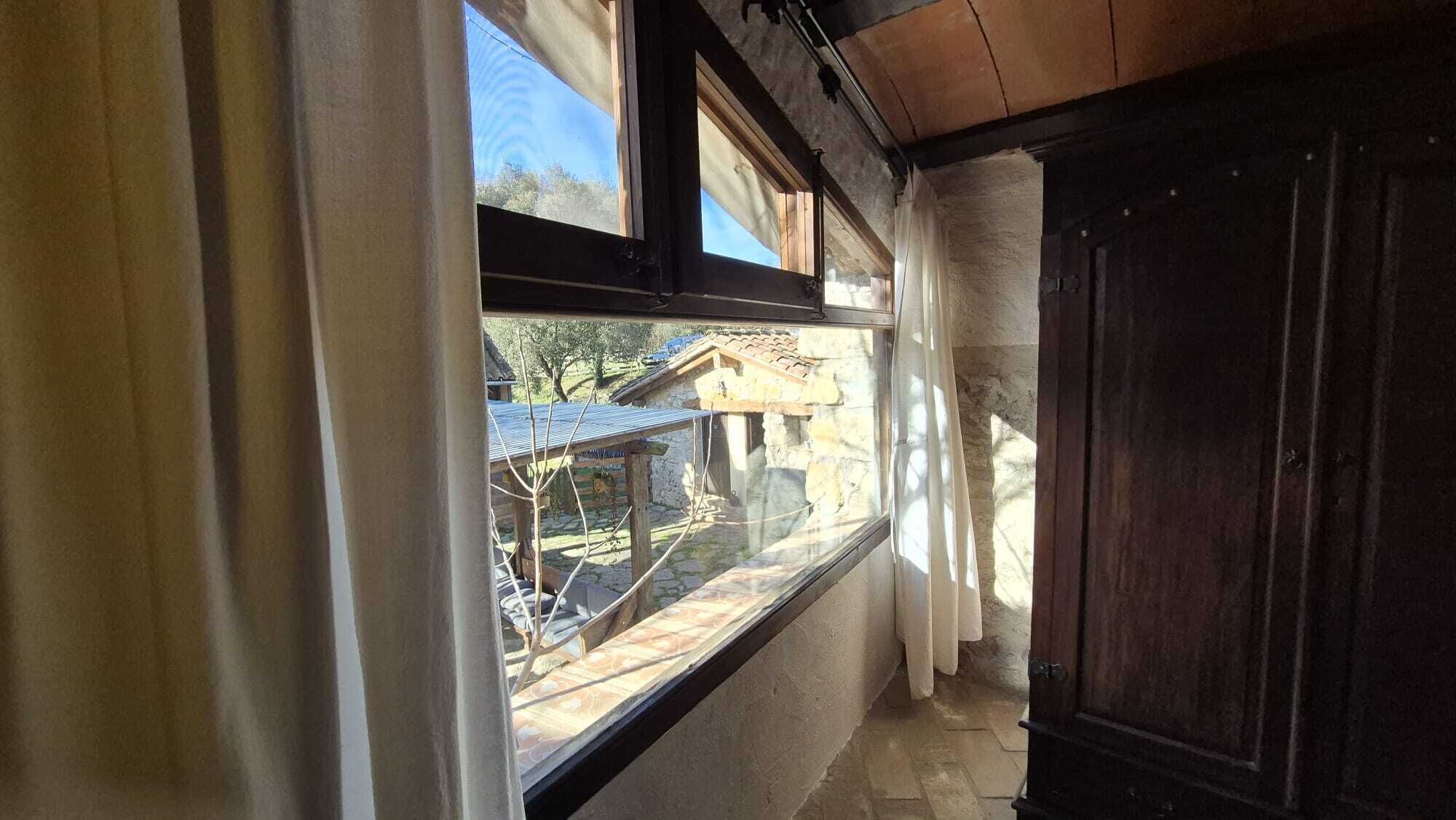 Un couloir étroit avec une fenêtre donnant sur un bâtiment dont le toit est recouvert de tuiles.