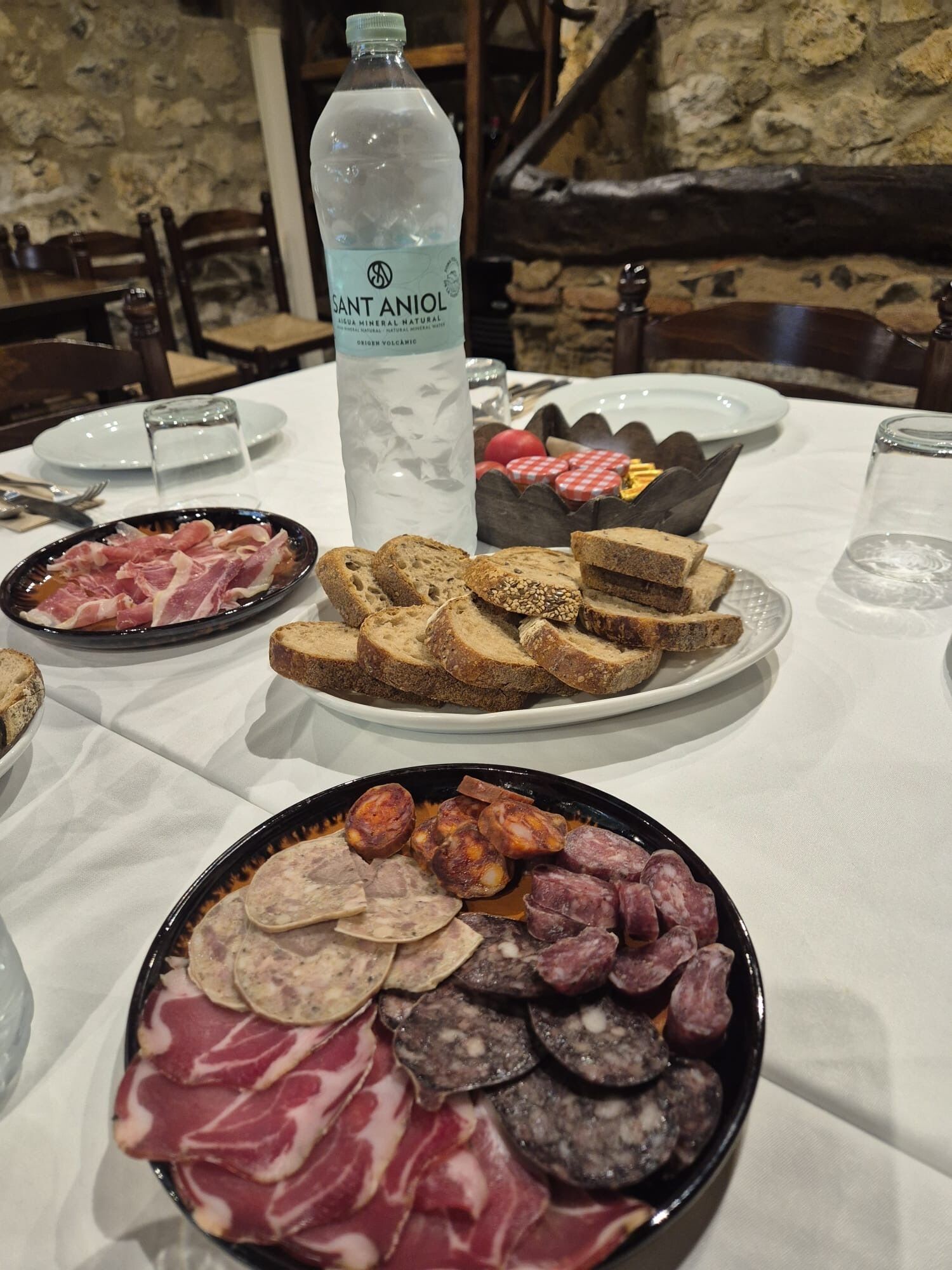 A table with various food items including bread, cured meats, and a bottle of water.