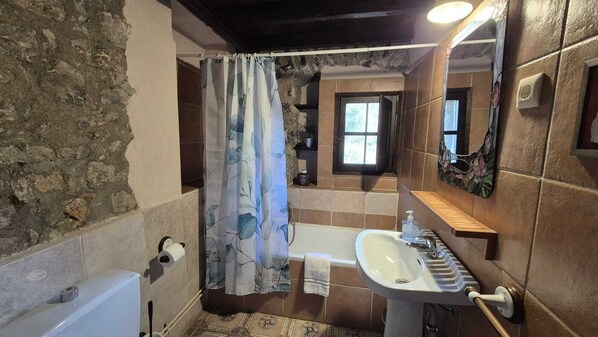 Une salle de bain avec une baignoire, un lavabo et un rideau de douche.