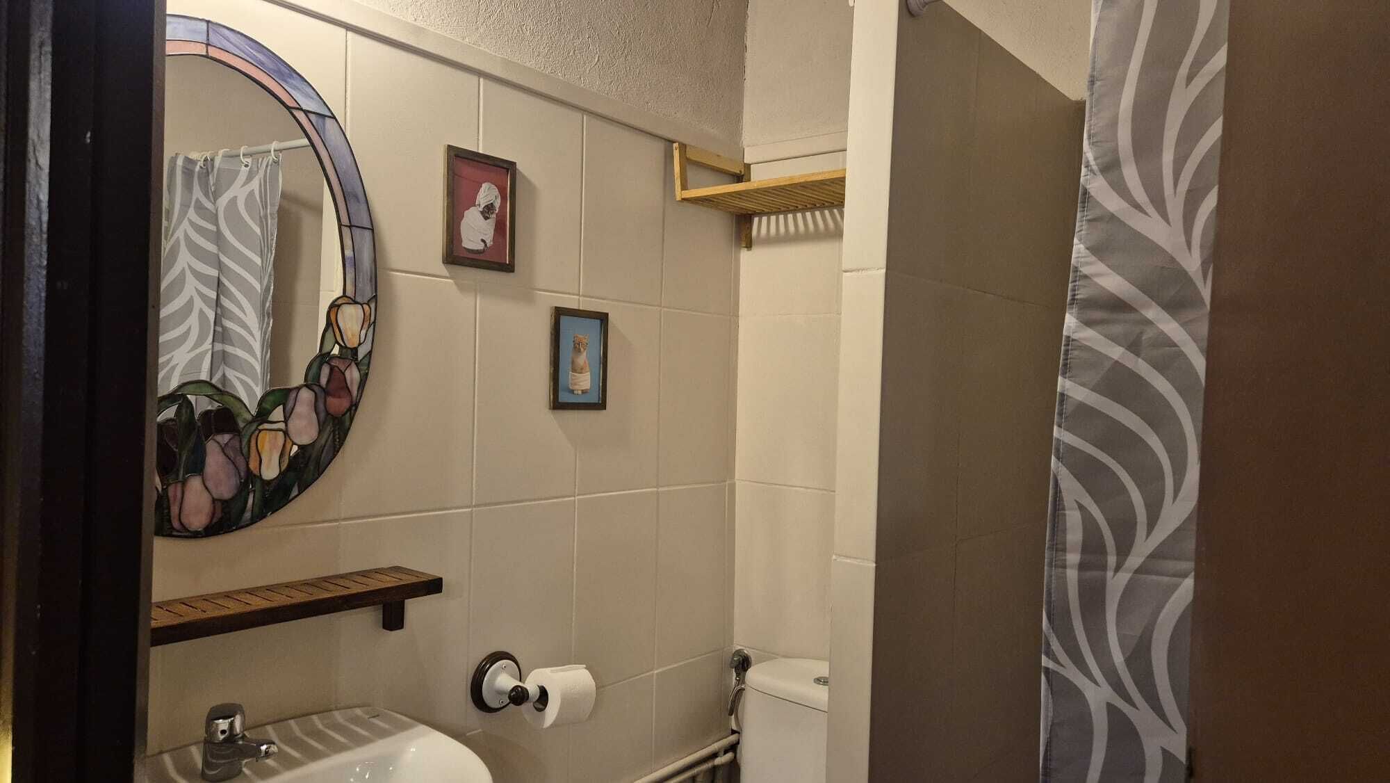 Un baño con inodoro, lavabo, espejo y perchero para toallas.