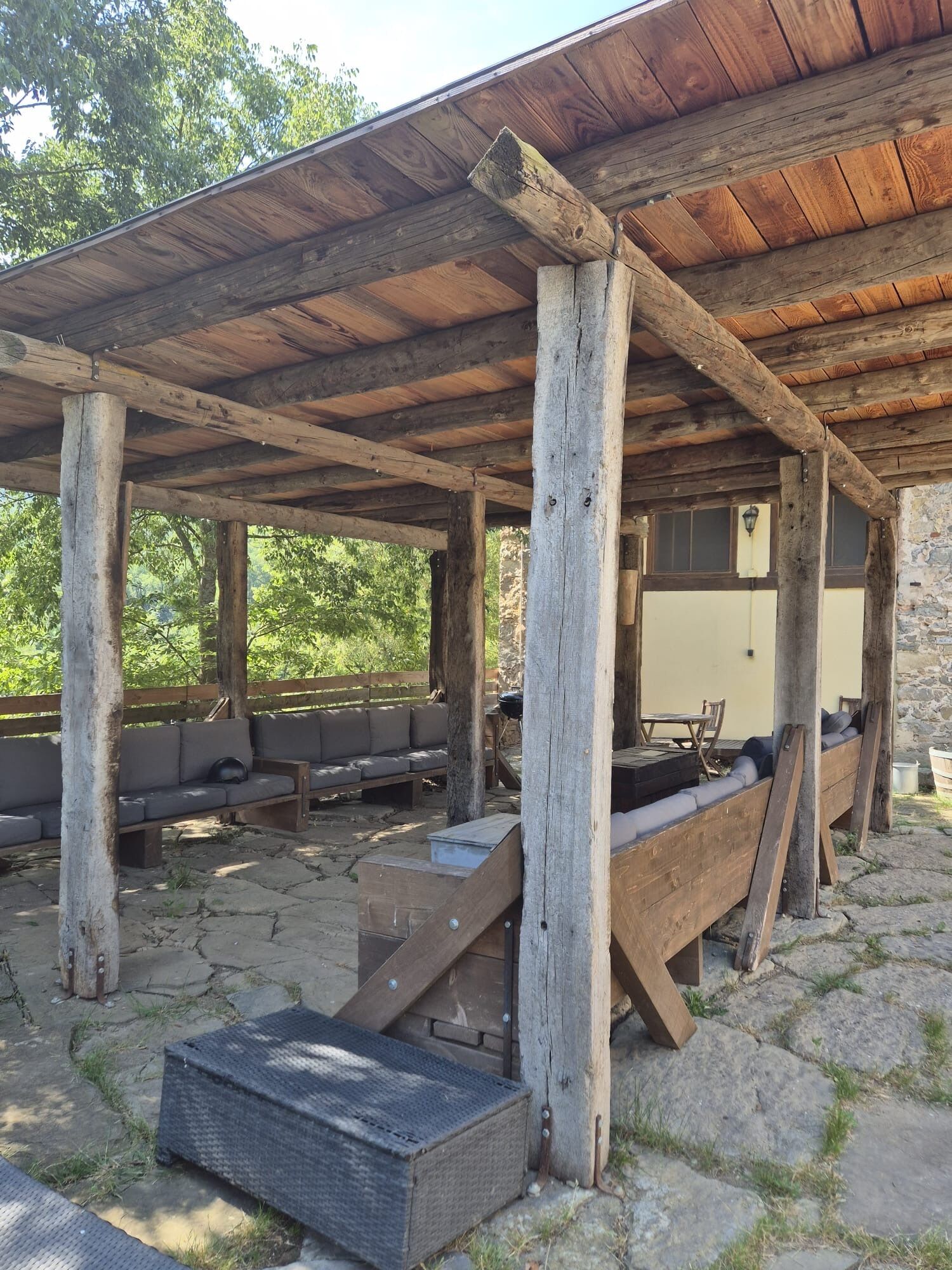 Un'area salotto esterna rustica con panche di legno e pavimento in pietra.