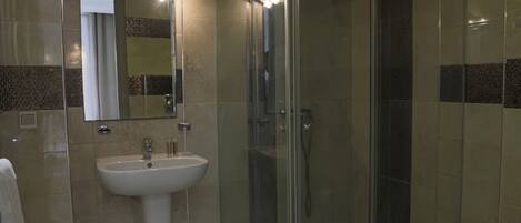 A bathroom with a glass-enclosed shower, a sink, and a mirror.