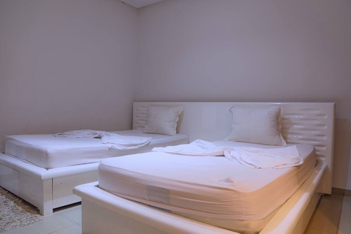 A bedroom with two single beds, a large bed, and a white headboard.