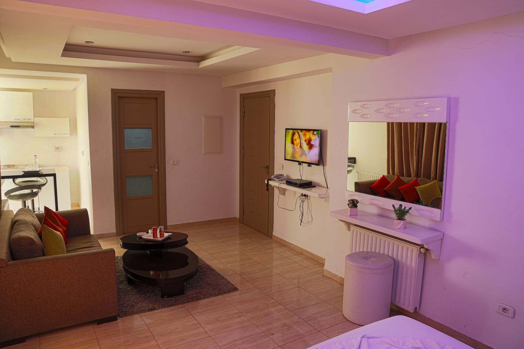 Una sala de estar moderna con sofá, mesa de centro, televisor y espejo.