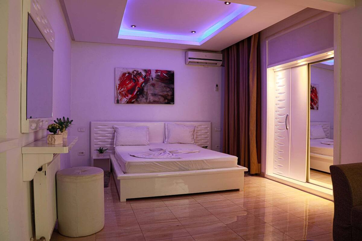 A modern bedroom with a bed, bedside table, and a wall-mounted air conditioner.