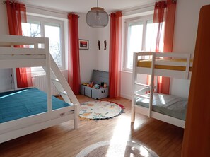 Ein Kinderzimmer mit Etagenbetten, einer Aufbewahrungsbox und einem Fenster.