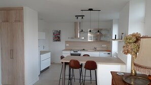 A modern kitchen with a dining area, wooden cabinets, and pendant lighting. - Fully Renovated Cottage in Basse Corrèze, Sleeps 8, Quiet and Scenic (Beynat)