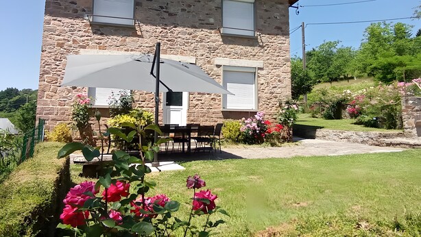 A stone house with a patio, outdoor seating, and a garden with flowers. - Fully Renovated Cottage in Basse Corrèze, Sleeps 8, Quiet and Scenic (Beynat)