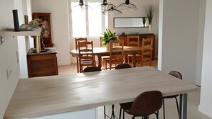 A modern kitchen with a large island, pendant lights, and a dining area with wooden chairs and a table. - Fully Renovated Cottage in Basse Corrèze, Sleeps 8, Quiet and Scenic (Beynat)