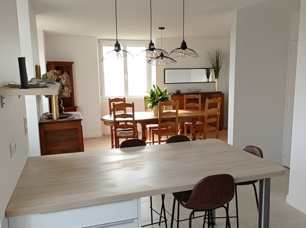 Eine moderne Küche mit einer großen Kochinsel, Pendelleuchten und einem Essbereich mit Holztischen und einem Tisch.