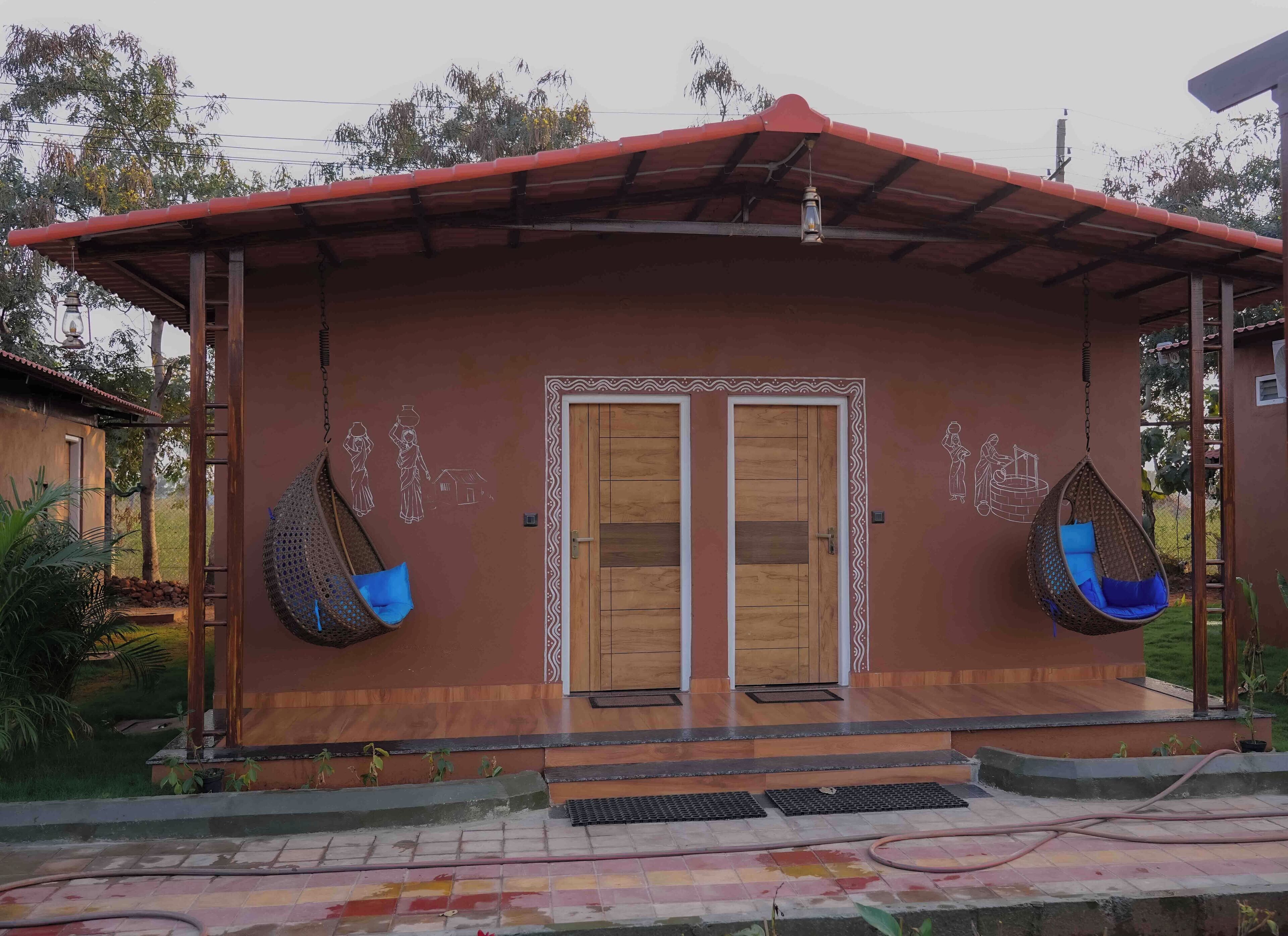 A two-story building with a red roof, a wooden door, and two hanging chairs.