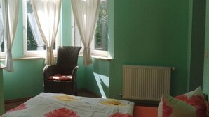 A room with a bed, a chair, a window with curtains, and a radiator.
