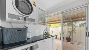A compact laundry room with a washing machine, dryer, and a sink. - Prime Location Crown, Train&City (Lathlain)