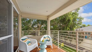 A balcony with two white chairs and a small table, a railing, and a view of trees and a yard. - Prime Location Crown, Train&City (Lathlain)