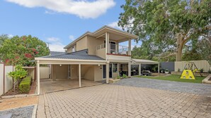 A two-story house with a covered patio area, a fenced yard, and a swing set. - Prime Location Crown, Train&City (Lathlain)