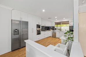 Una cocina moderna con armarios blancos, electrodomésticos de acero inoxidable y piso de madera.