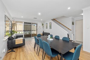 Un comedor moderno con una mesa de madera oscura, sillas azules y un sofá negro.